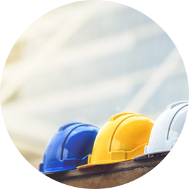 Three construction helmets (blue, yellow, and white) resting on a ledge with a modern building in the background